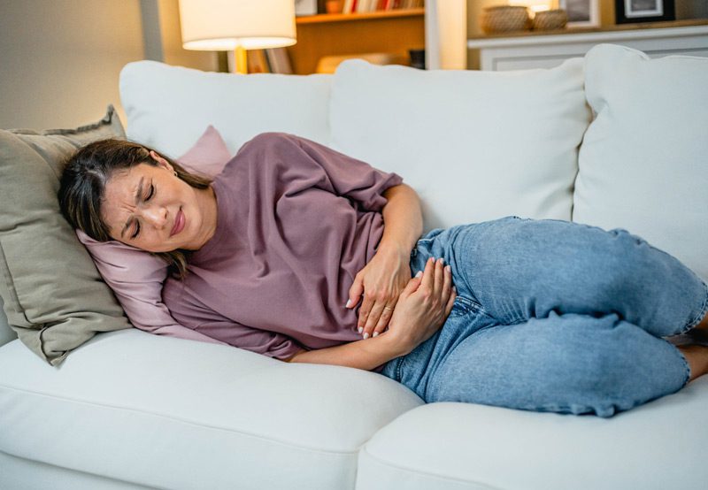 Woman-lying-on-the-couch-with-abdominal-pain